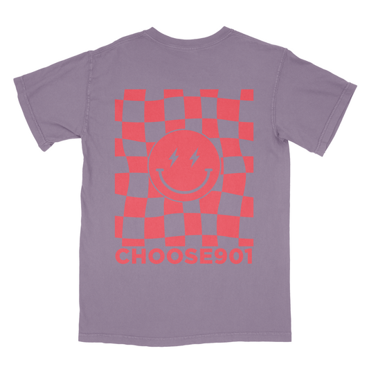 A purple Comfort Colors t-shirt with a red and orange checkered design around a central circle featuring lightning bolts and the Choose901 Lightning Smiley on Berry text below from Choose901 Merch Shop.